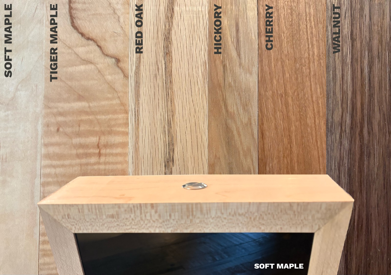 Six labeled wood boards side by side &mdash; soft maple, tiger maple, red oak, hickory, cherry, and walnut &mdash; with the mitered soft maple top of the box and its stainless ask button in front